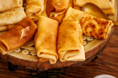 Yumuşak altın krepler katlanır ve ahşap servis tabağına düzgünce yerleştirilir..