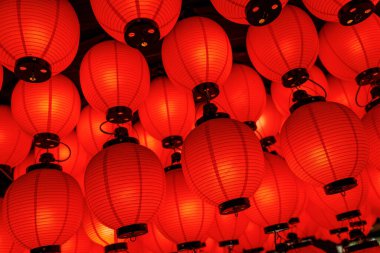 Geleneksel yuvarlak kırmızı fenerlerden oluşan yoğun bir düzenleme içeriden aydınlatıldı. Çekim dokuyu ve sıcak ışığı vurguluyor..