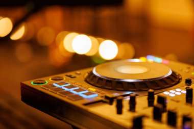 Yakından bakıldığında, profesyonel bir karıştırma konsolu jog tekerleği ve koyu bir ortamda aydınlanan sönücüleri gösterir.