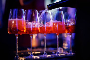 Portakallı aperatifle dolu şarap kadehleri ve üzerine koyu bir ortamda bardaktan doldurulmuş buz..