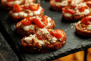 Krem peynirli, güneşte kurutulmuş domatesli ve parmesanlı rendelenmiş ekmek diliminin detaylı bir çekimi..