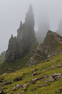 Yoğun bir sabah sisinde Skye Adası 'nın yeşil yamaçlarında dramatik bir bazalt kulesi beliriyor..