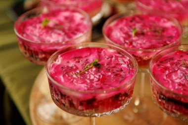 Canlı pembe bir sebze köpüğüyle dolu cam kaseler ve taze yeşilliklerle süslenmiş. Bu porsiyonlar bir yemek organizasyonu için ayarlandı..