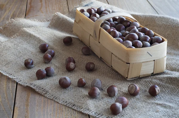 Орешки в плетеной корзине на деревянном столе . — стоковое фото