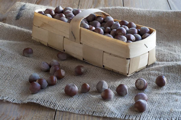 Huzelnuts in un piccolo cesto di vimini su un tavolo di legno . — Foto Stock