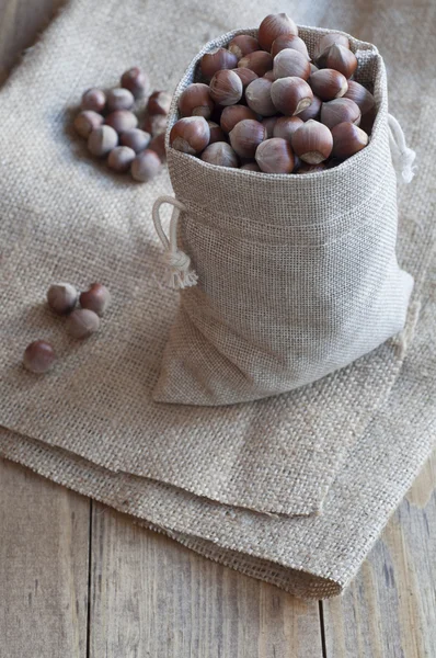 Орехи в хлопчатобумажном мешке на деревянном столе . — стоковое фото