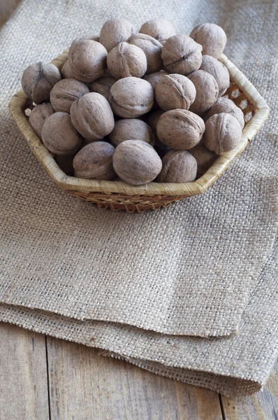 Walnuts on a wooden table covered with burlap. — Stock Photo, Image