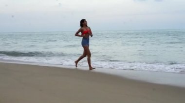Asyalı kız yogası silueti kollarını kaldırarak özgür hissetmek ve sabahın ilk ışıklarıyla sahilde hayatın tadını çıkarmak için. Özgürlük ve refah kavramı..
