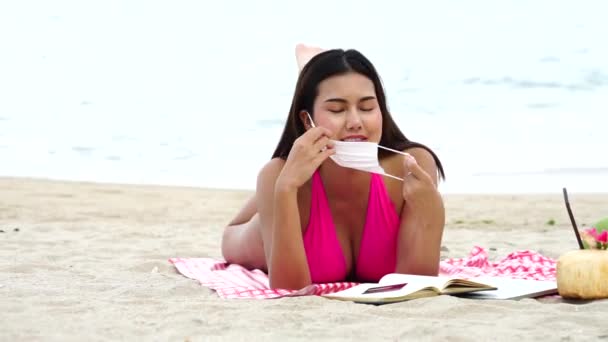 수영복을 마스크를 카드를 휴가를 즐기며 아름다운 모래사장에서 일광욕을 즐기는 아시아 — 비디오