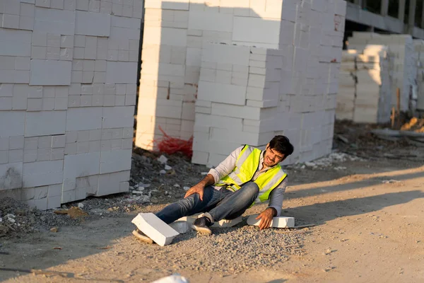 Foreman, inşaat projesinde yürüyen bir adam, iş sırasında tuğla ve havan topu kazası geçirdi, ayak bileğini incitti..