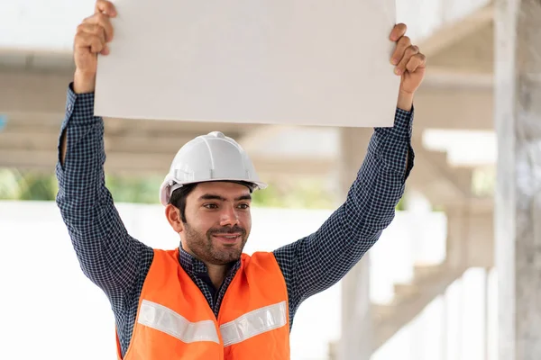 Workers wearing engineer helmets hold strike banners to raise minimum wages at the construction of a housing complex.