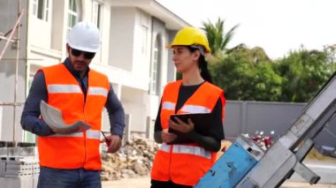 Güzel kadın mühendis ve koruyucu miğfer takan erkek ustabaşı çalışma problemlerinden, inşaat projeleriyle ilgili konuşuyorlar..