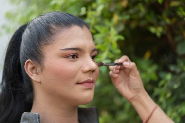 Evdeki bahçeye güzel bir bakış atmak için yanakları öne çıkaran bir sanatçı. Güzellik ve LGBT konsepti