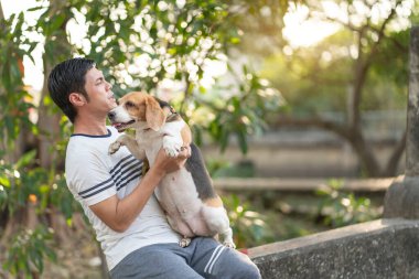 Genç Asyalı bir adam sabah bir av köpeğiyle koşuya çıkar, koşmak için durur ve sevdiği hayvanlarıyla bahçede oturur.. 