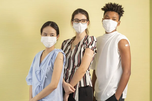 A group of young, multinational Asian, white women and African American men vaccinating their plastered arms feel safe from contracting COVID-19.