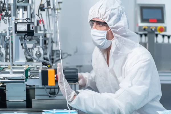 Technicians wearing PE protective clothing and anti-glare goggles control the production of mask factories.