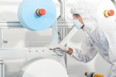 Üretim hattı çalışanları ve uzmanları fabrikada kaliteli maskeler üretmek için ham kumaş üretimini kontrol ediyorlar.. 