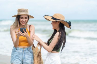 Asya 'da iki kız arkadaş yaz tatilinde sahilde silmek için akıllı telefonlar kullanarak seyahat ediyor.. 