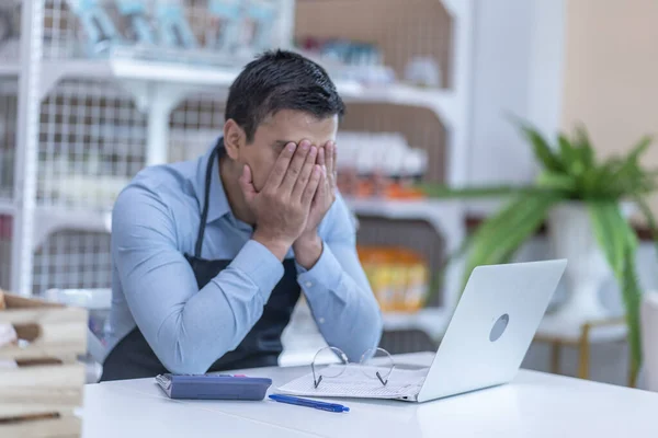 Bir marketi olan küçük işletme sahibi dükkanda önlük giyer, envanter hesaplarını kontrol eder ve internet üzerinden iş yapar.. 