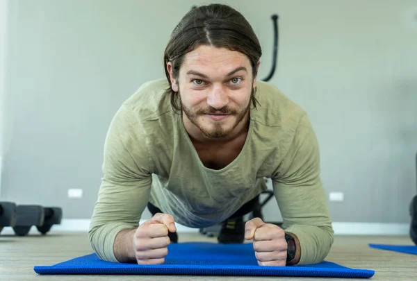 Yakışıklı adam spor salonundaki yoga minderleri üzerinde yoga egzersizleri yapmaktan ve nefes almadan egzersiz yapmaktan hoşlanıyor.. 