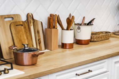 Mutfak aletleri mutfaktaki tezgahın üzerinde. Tencere, tahta kesme tahtaları, bıçaklar. Mutfağın içinde İskandinav tarzı