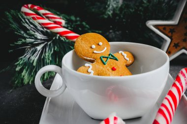 Beyaz bardaktaki zencefilli adam. Karanlık bir arka planda Noel kurabiyesi. tatil kartı