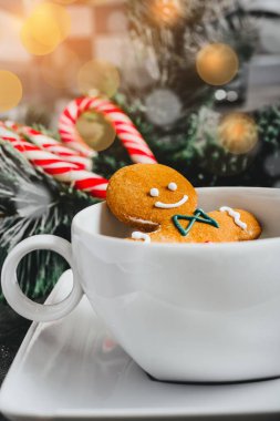 Beyaz bardaktaki zencefilli adam. Karanlık bir arka planda Noel kurabiyesi. tatil kartı