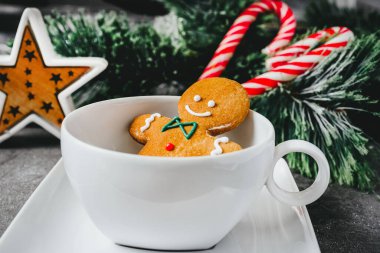 Beyaz bardaktaki zencefilli adam. Karanlık bir arka planda Noel kurabiyesi. tatil kartı