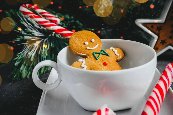 Beyaz bardaktaki zencefilli adam. Karanlık bir arka planda Noel kurabiyesi. tatil kartı
