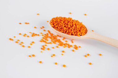 Beyaz arka planda kırmızı mercimek olan tahta kaşık. makro fotoğraf. sağlıklı vejetaryen yemeği. ulusal Asya yemeği