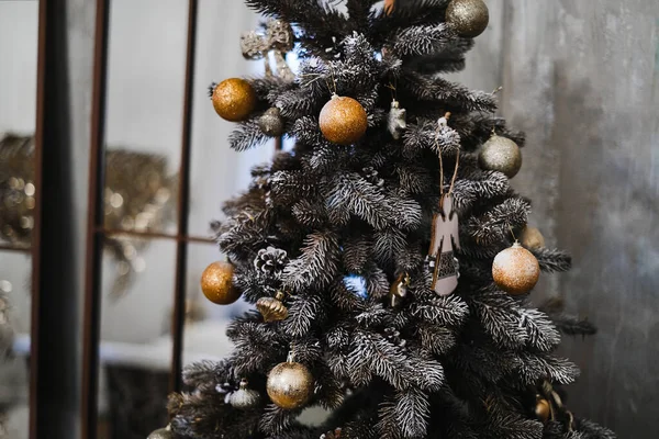 Yapay Noel ağacı, altın toplar ve ahşap oyuncaklarla süslenmiş, barok bir iç mekanda. Noel için süslemeler. Yeni yılın atmosferi