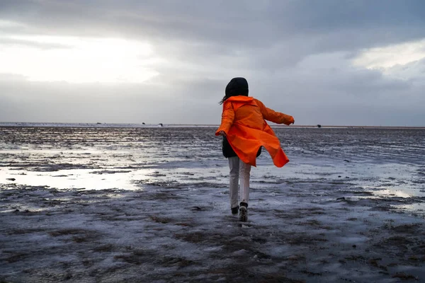비옷을 소녀가 눈덮인 들판을 지릅니다 겨울에는 아이슬란드의 자연에 영향을 않는다 — 스톡 사진