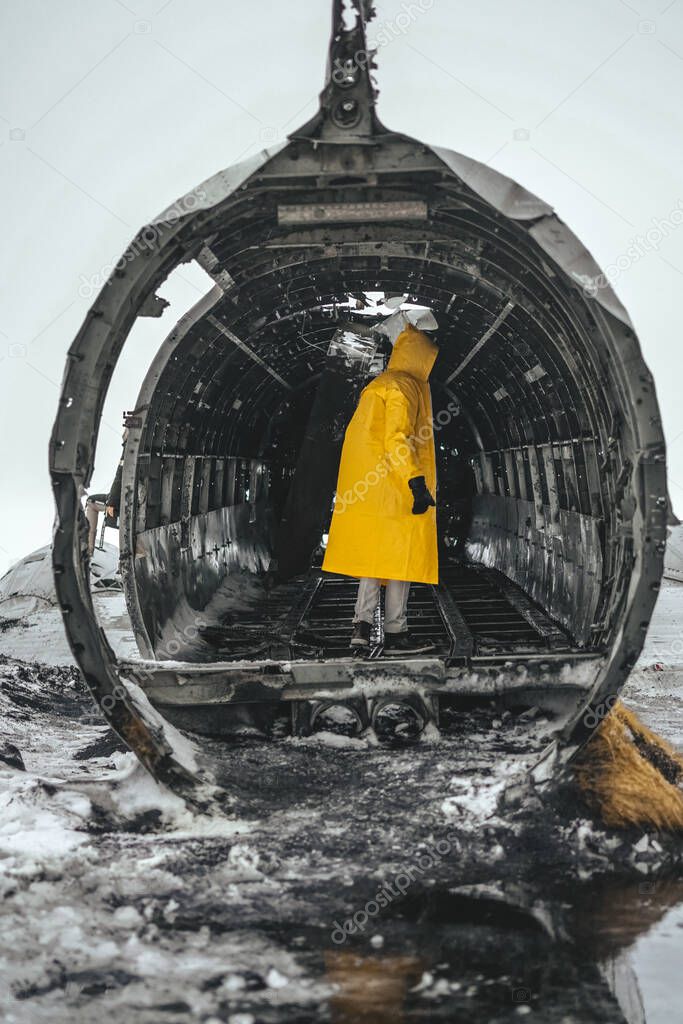 man in yellow raincoat inside DC-3 plane crashed in Slheimasandur. Attractions of Iceland. Iceland, December 2020