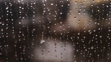 Yağmur damlaları pencereye yakın planda akıyor. Sonbahar havası. Dışarıda sağanak yağmur. Damlaların kapanışı