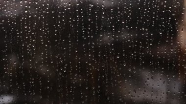 Yağmur damlaları pencereye yakın planda akıyor. Sonbahar havası. Dışarıda sağanak yağmur. Damlaların kapanışı