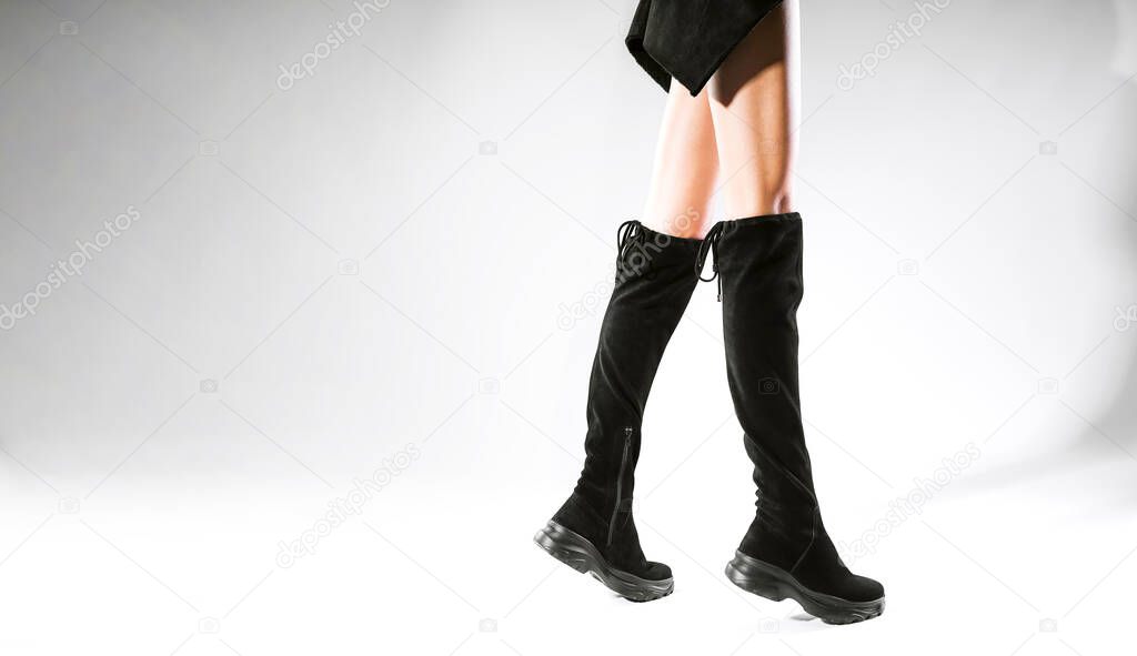 legs of the girl in fashionable black boots on a white background in the studio. stylish fashion boots autumn winter