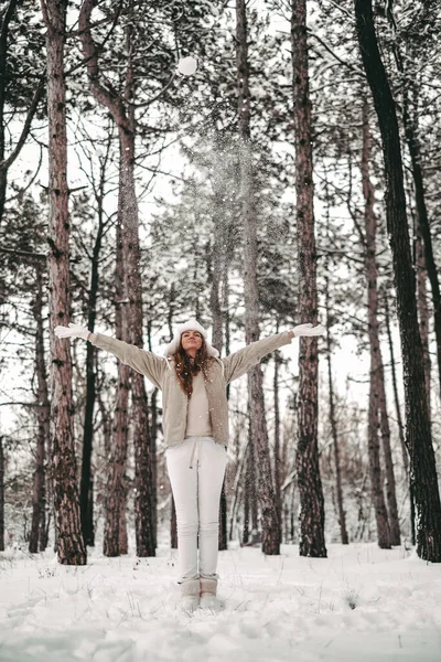 身穿白毛帽和白衣的漂亮女孩在雪地的森林里玩得很开心 年轻女人扔雪 做雪球 大自然的冬季娱乐活动 — 图库照片