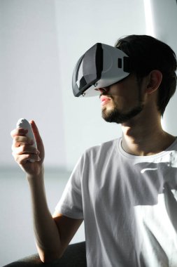 Genç bir adam sanal gerçeklik gözlükleriyle sanal bir oyun oynuyor. Evde kendini izole etmek için boş zaman. Sanal gerçeklik. Sanal gerçeklik gözlüğü takan yakışıklı bir gencin portresi.