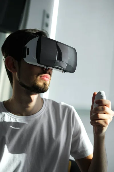 a young man plays a virtual game in VR glasses. home leisure on self-isolation at home. The virtual reality. portrait of handsome young man wearing virtual reality glasses