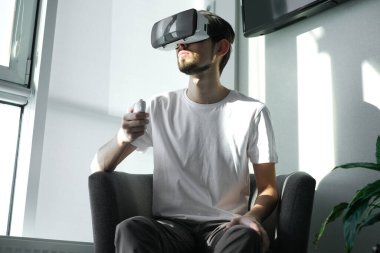 Genç adam kontrol paneliyle güçlü bir şekilde sanal gerçeklik oyunu oynuyor. Adam video oyunu oynuyor. Biraz rahatla. Neşeli bir hafta sonu. Video oyununa odaklan. Oyunu kazanmak, kumar oynamak. Çoklu Oyuncu ga