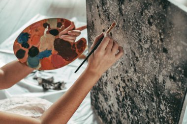 Genç ve güzel bir kız, kendini izole etmek için siyah beyaz yağlı boya resim çiziyor. Sanat terapisi. Ev tatili. resim atölyesi