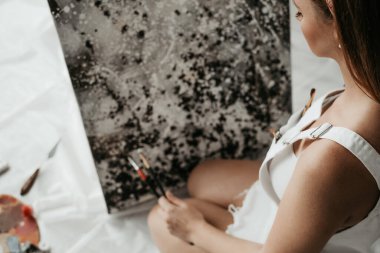 Genç ve güzel bir kız, kendini izole etmek için siyah beyaz yağlı boya resim çiziyor. Sanat terapisi. Ev tatili. resim atölyesi