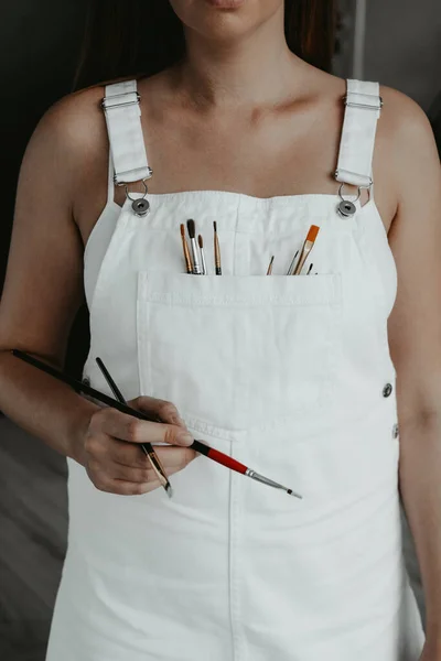一个年轻的女画家穿着白色的太阳衣 用调色板作画和刷子作画的肖像 女人孤立无援地在家里画一幅画 艺术疗法 愉快的周末 — 图库照片