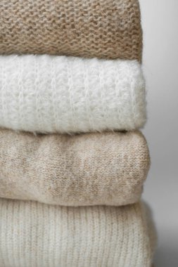 Beyaz bej ve beyaz doğal yün kazaklar, beyaz arka planda katlanmış. Merino yününden giysiler, alpaka, doğal eko-kumaşlar. Bilinçli tüketim kavramı. düz yat