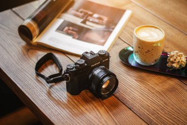 Masada dergi ve kahveyle birlikte profesyonel aynasız kamera Fujifilm var. Fotoğrafçının sabah çalışması. Odessa, Ukrayna Şubat
