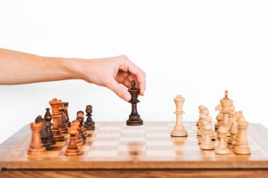 Adam satranç taşını eliyle tutuyor. Satranç tahtası. Beyaz arka planda satranç oyunu. satranç turnuvası