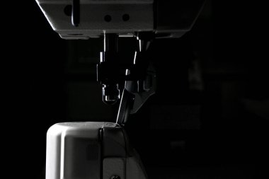 Siyah arka planda yakın plan üretim dikiş makinesi. Profesyonel bir dikiş makinesinin detayları. maketleme