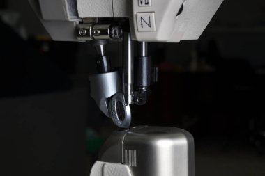 Siyah arka planda yakın plan üretim dikiş makinesi. Profesyonel bir dikiş makinesinin detayları. maketleme