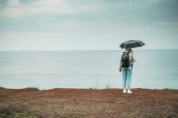 우산으로 두르고 절벽에 뒤에서 바다를 바라본다 아름다운 — 스톡 사진