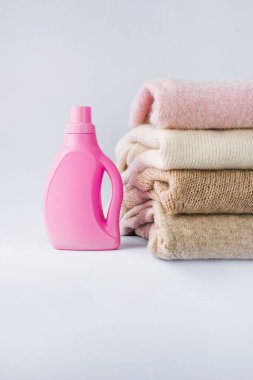 Beyaz bir arka planda katlanmış, çamaşır jeli ve durulama ile yün renkli açık renk elbiseler. maketleme